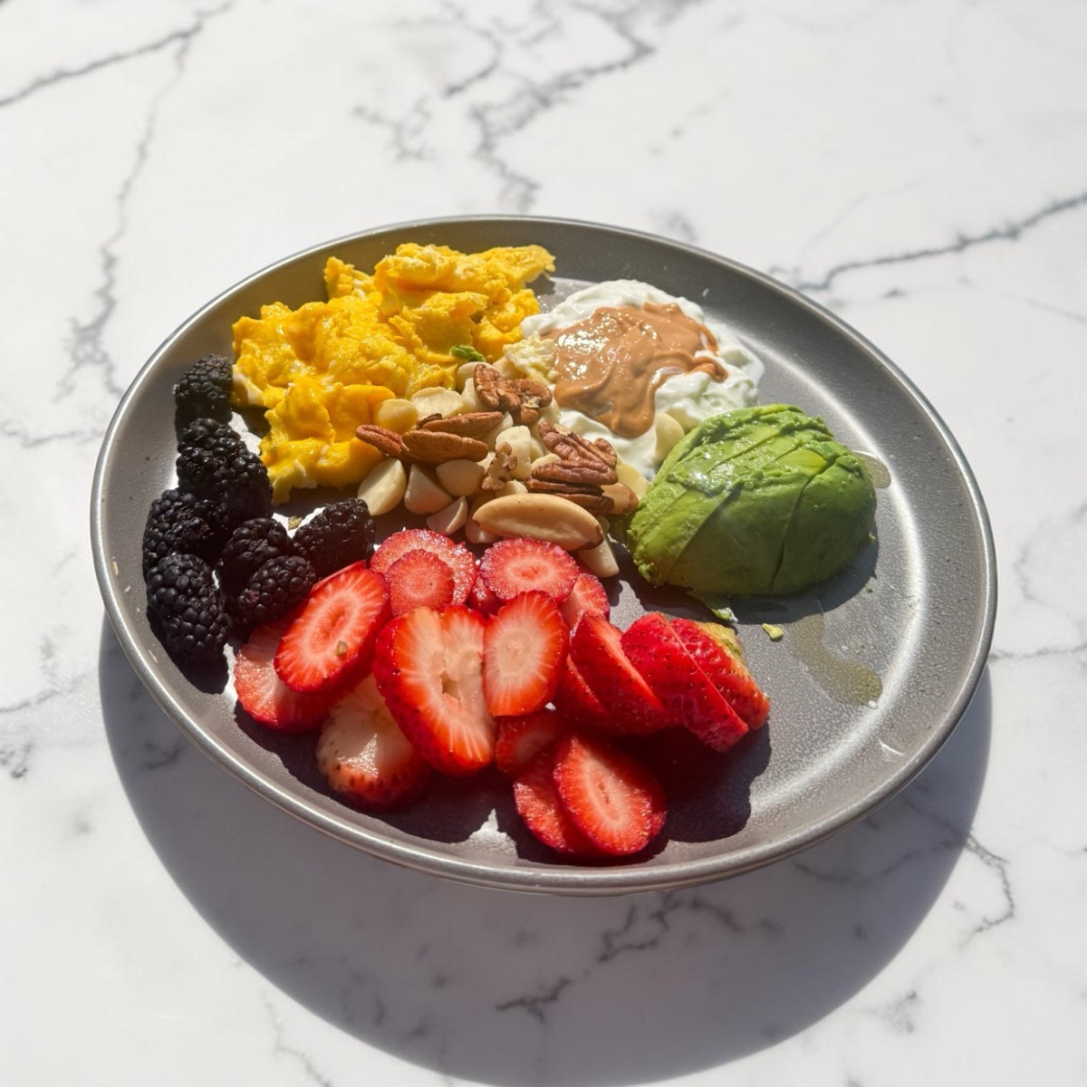 A breakfast plate: berries, nuts, avocado