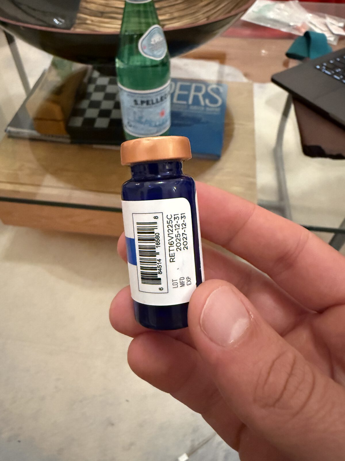 The same vial turned around: a printed label with a barcode, lot number RET16V1225C, manufacture date and expiry